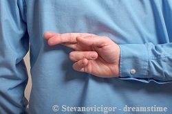 Man in blue shirt crossing his fingers at his back