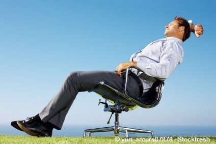 Man in formal dress relaxing in a revolving chair outside office