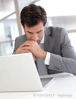 a businessman in deep thoughts while seriously looking on his computer screen